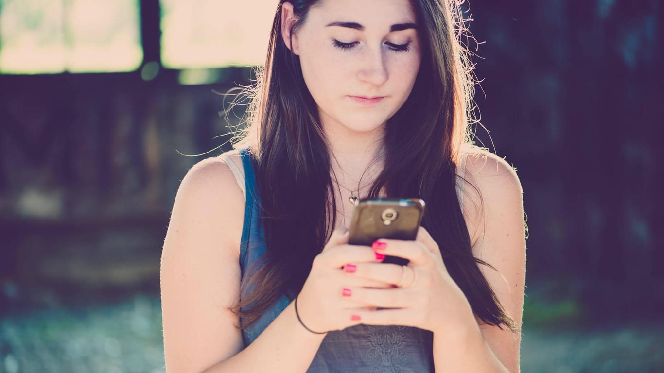 Mädchen mit Smartphone: Kinder unter 16 Jahren müssen künftig auf WhatsApp verzichten.