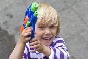 Kleines Mädchen spielt mit Wasserpistole. Google will sein Pistolen-Emoji gegen eine Spielzeugwaffe eintauschen.