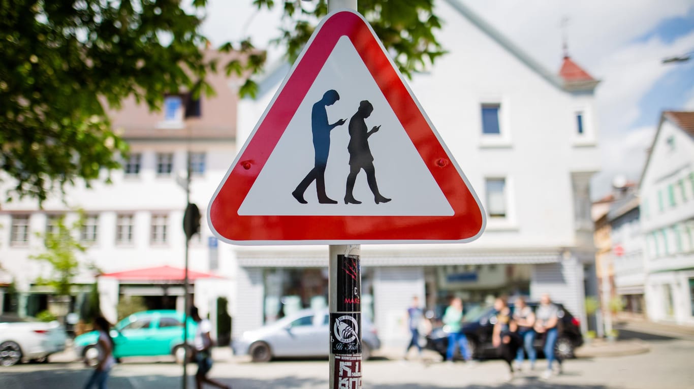 Ein Schild warnt an einer Straße neben einer Schule in Reutlingen (Baden-Württemberg) vor "Smombies": Die Abkürzung ist ein Kunstwort für "Smartphone und Zombie".