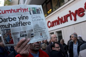 Ein Mann hält eine Ausgabe der Zeitung vor der "Cumhuriyet"-Zentrale in Istanbul (Türkei) in die Luft: Mehrere führende Mitarbeiter der Zeitung haben in der Türkei mehrjährige Haftstrafen erhalten. (Archivbild)