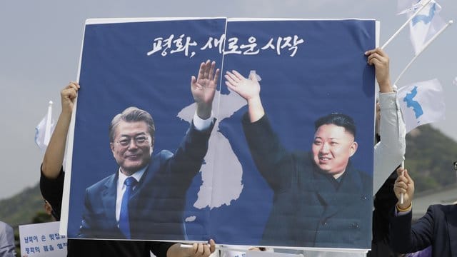 Nordkoreas Machthaber Kim Jong Un (r) und der südkoreanische Präsident Moon Jae sind in Seoul auf einem Plakat von Aktivisten zu sehen. Nordkoreas Machthaber Kim Jong Un (r) und der südkoreanische Präsident Moon Jae sind in Seoul auf einem Plakat von Aktivisten zu sehen.