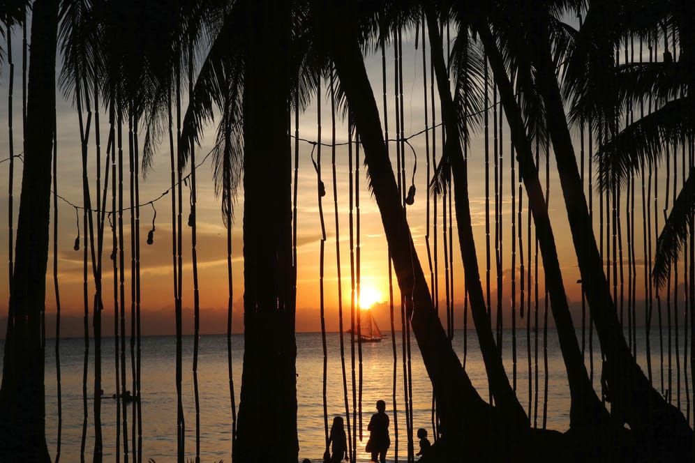 Insel Boracay (Philippinen): Menschen stehen bei Sonnenuntergang am Strand.