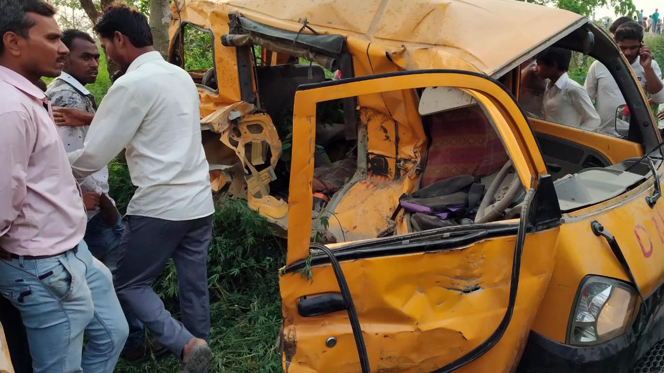 Inder stehen an einer Unfallstelle vor verunglücktem Schulbus: Bei der Kollision eines Zuges mit einem Schulbus sind mindestens 13 Kinder ums Leben gekommen.