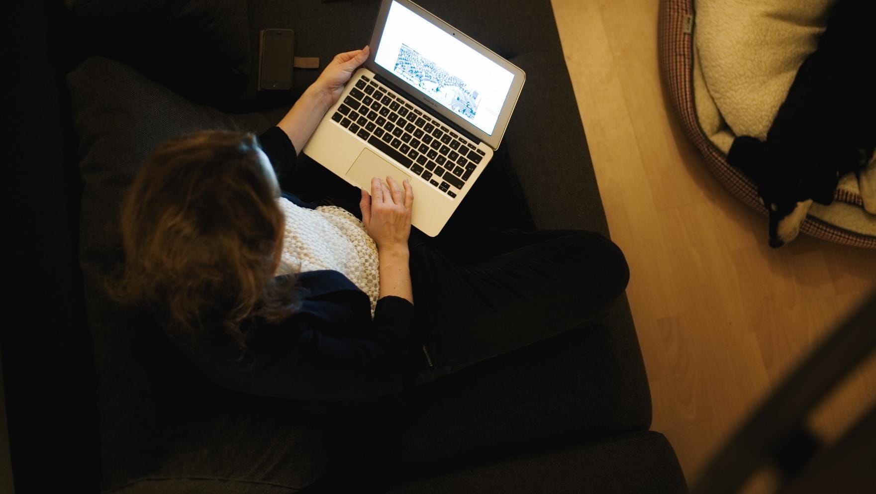 Eine Frau sitzt auf der Couch ihrer Wohnung und arbeitet am Laptop: FDP und Union wollen mit der Flexibilisierung der Arbeitszeit die Vereinbarkeit zwischen Beruf und Familie verbessern.