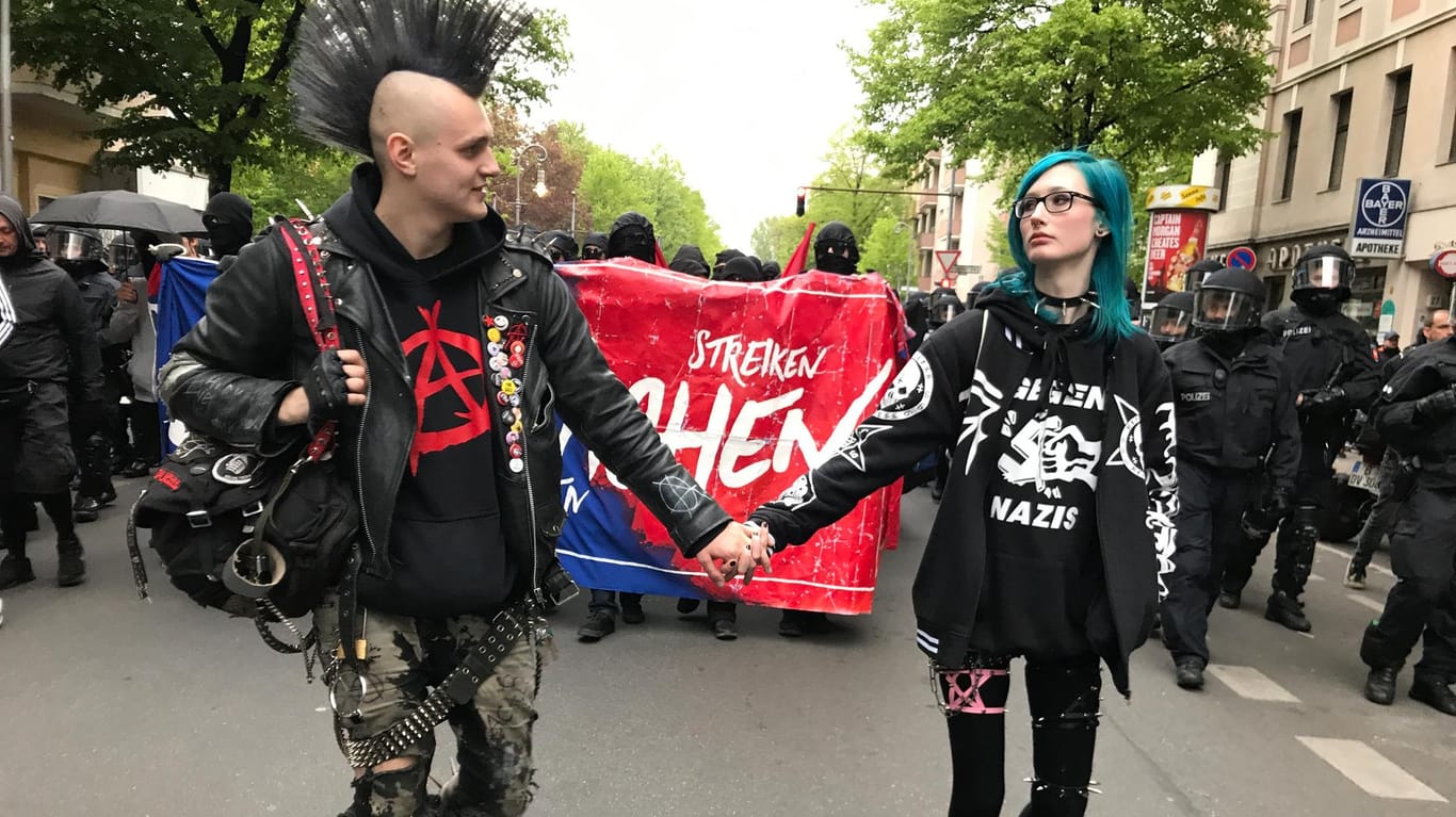 Ein Punker-Paar schlendert Händchen haltend auf einer Maikundgebung in Berlin.