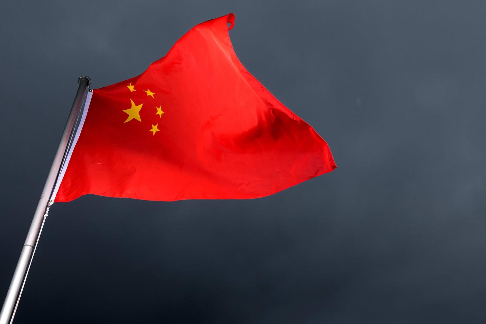Die Flagge Chinas weht im Wind vor schwarz-grauem Himmel: Ein Messerstecher tötete sieben Kinder auf dem Heimweg von der Schule.