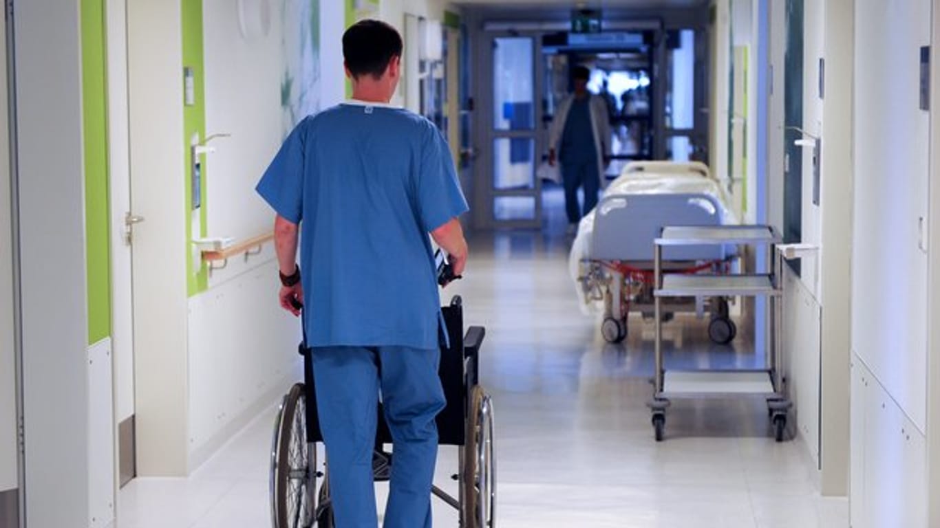 Ein Pfleger schiebt einen Rollstuhl.