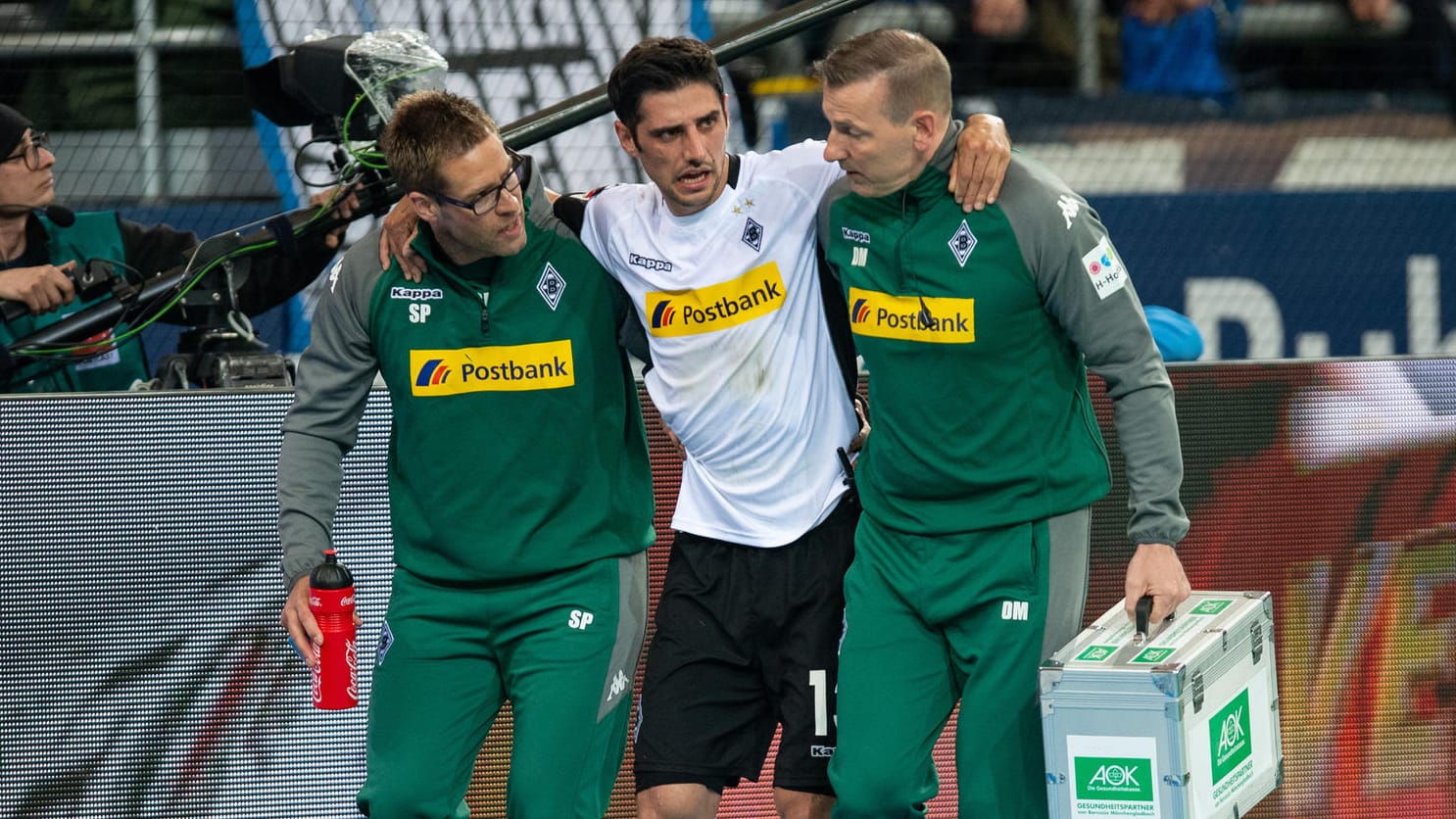 Gladbachs Lars Stindl wird von zwei Betreuern gestützt und muss verletzungsbedingt ausgewechselt werden.