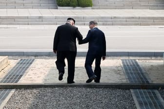 Kim Jong Un (L), Machthaber von Nordkorea, und Moon Jae In, Präsident von Südkorea, gehen Hand in Hand über die Betonschwelle, die die Grenze zwischen ihren Ländern markiert.