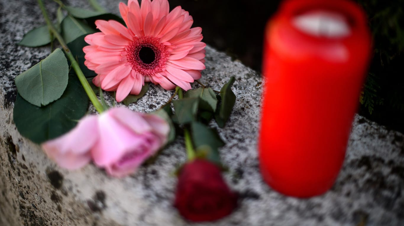 Blumen und Kerzen liegen bzw. stehen auf einer Mauer vor dem Haus, in dem ein Siebenjähriger tot aufgefunden wurde.