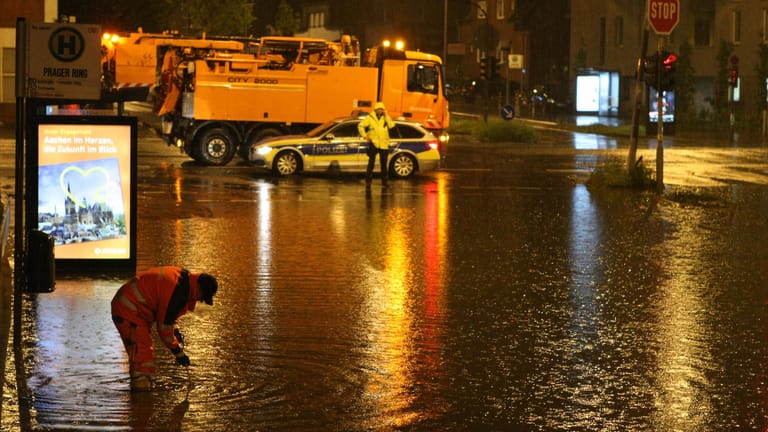 Knietief steht eine Einsatzkraft im Wasser: Hunderte Notrufe gingen bei der Polizei ein.