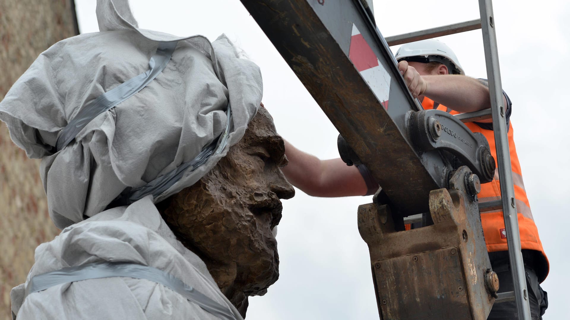 Karl Marx in Trier: Ein Arbeiter zieht eine Plane vom Kopf der 2,3 Tonnen schweren und 4,40 Meter großen Statue des chinesischen Künstlers Wu Weishan.