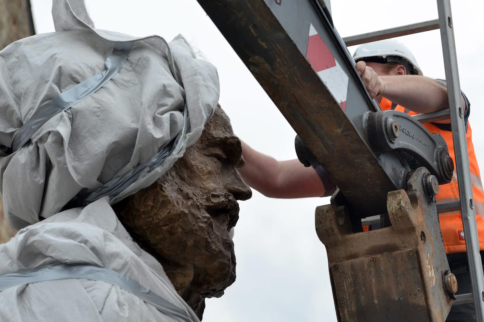 Karl Marx in Trier: Ein Arbeiter zieht eine Plane vom Kopf der 2,3 Tonnen schweren und 4,40 Meter großen Statue des chinesischen Künstlers Wu Weishan. Karl Marx in Trier: Ein Arbeiter zieht eine Plane vom Kopf der 2,3 Tonnen schweren und 4,40 Meter großen Statue des chinesischen Künstlers Wu Weishan.