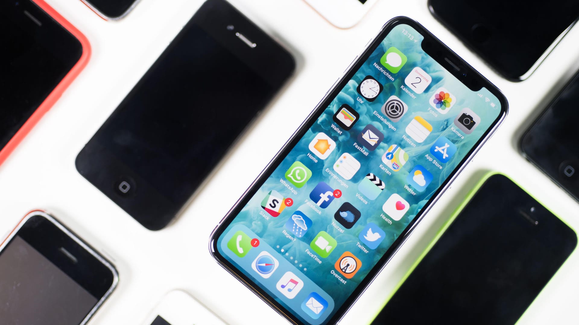 Ein iPhone X liegt zwischen anderen Smartphones aus.