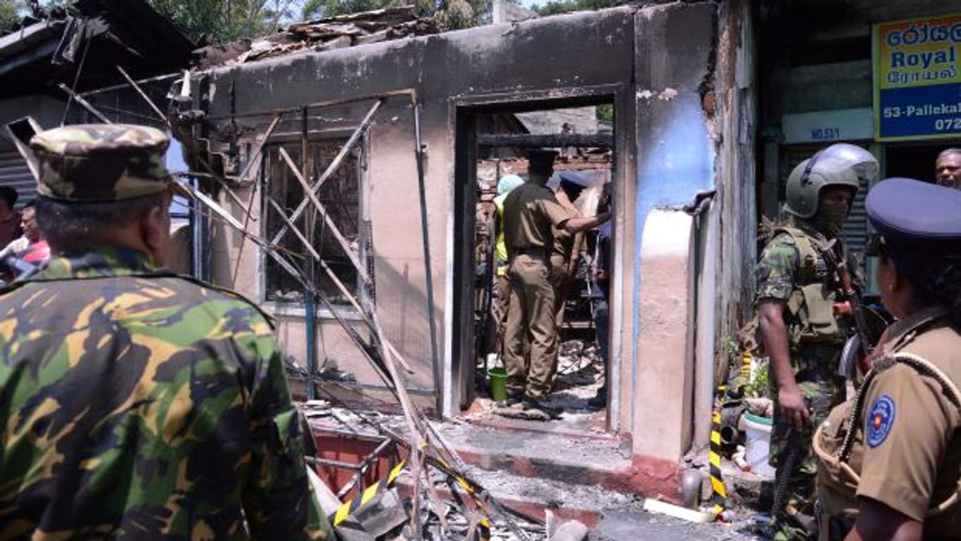 Soldaten vor einem abgefackelten Haus in Sri Lanka