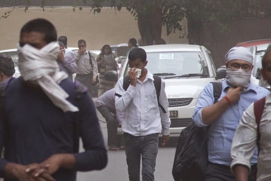 Leute schützen sich in Neu Delhi mit Tüchern vor einem Staubsturm.
