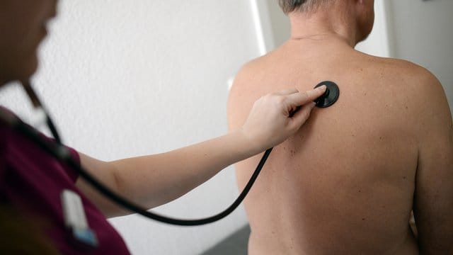 Eine Medizinerin untersucht einen Patienten mit einem Stethoskop. Eine Medizinerin untersucht einen Patienten mit einem Stethoskop.