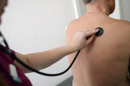 Eine Medizinerin untersucht einen Patienten mit einem Stethoskop.