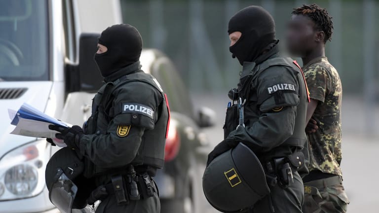 Erstaufnahmeeinrichtung für Flüchtlinge (LEA) in Ellwangen: Ein gefesselter Mann wird von maskierten Polizisten während des Großeinsatzes am Donnerstag abgeführt.