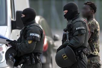Erstaufnahmeeinrichtung für Flüchtlinge (LEA) in Ellwangen: Ein gefesselter Mann wird von maskierten Polizisten während des Großeinsatzes am Donnerstag abgeführt.