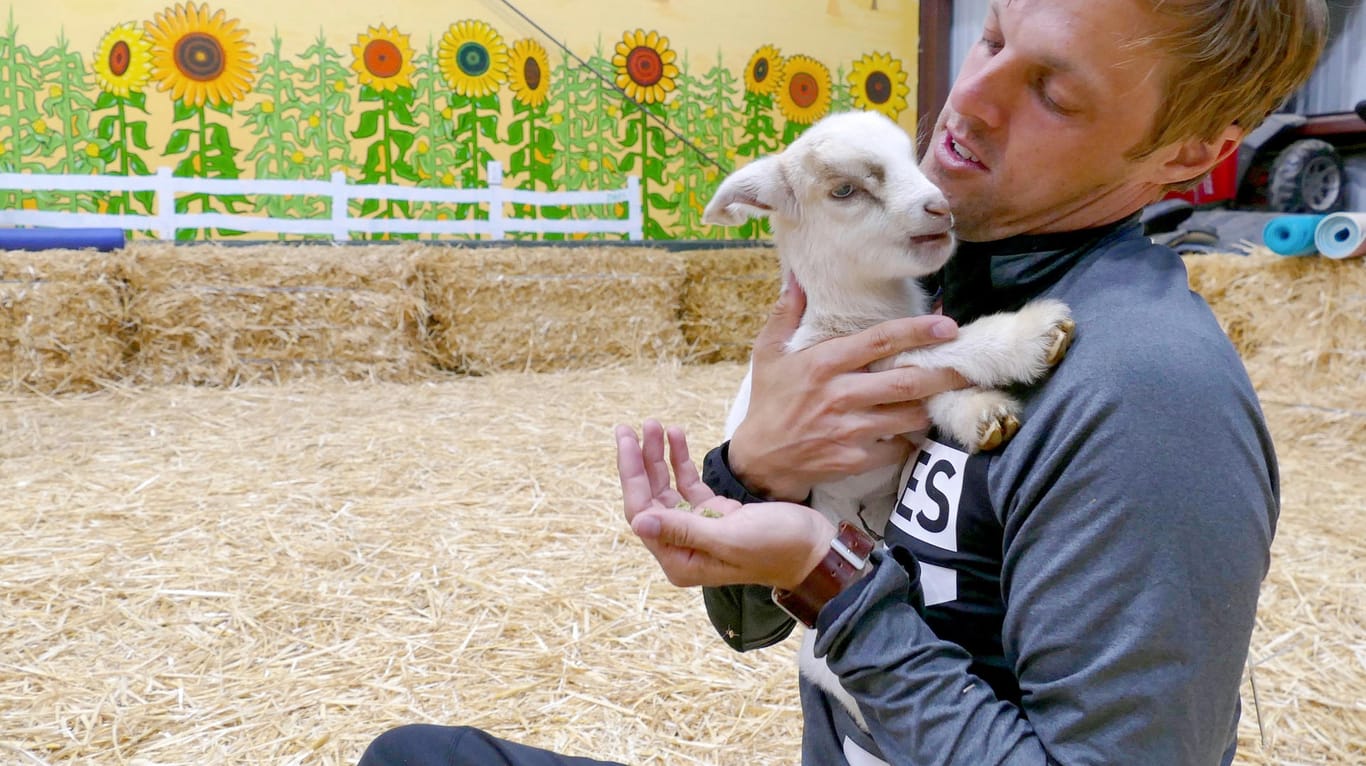 Patrick Stanier, Teilnehmer eines Yoga-Kurses mit Ziegen, hält eine Zwergziege im Arm.