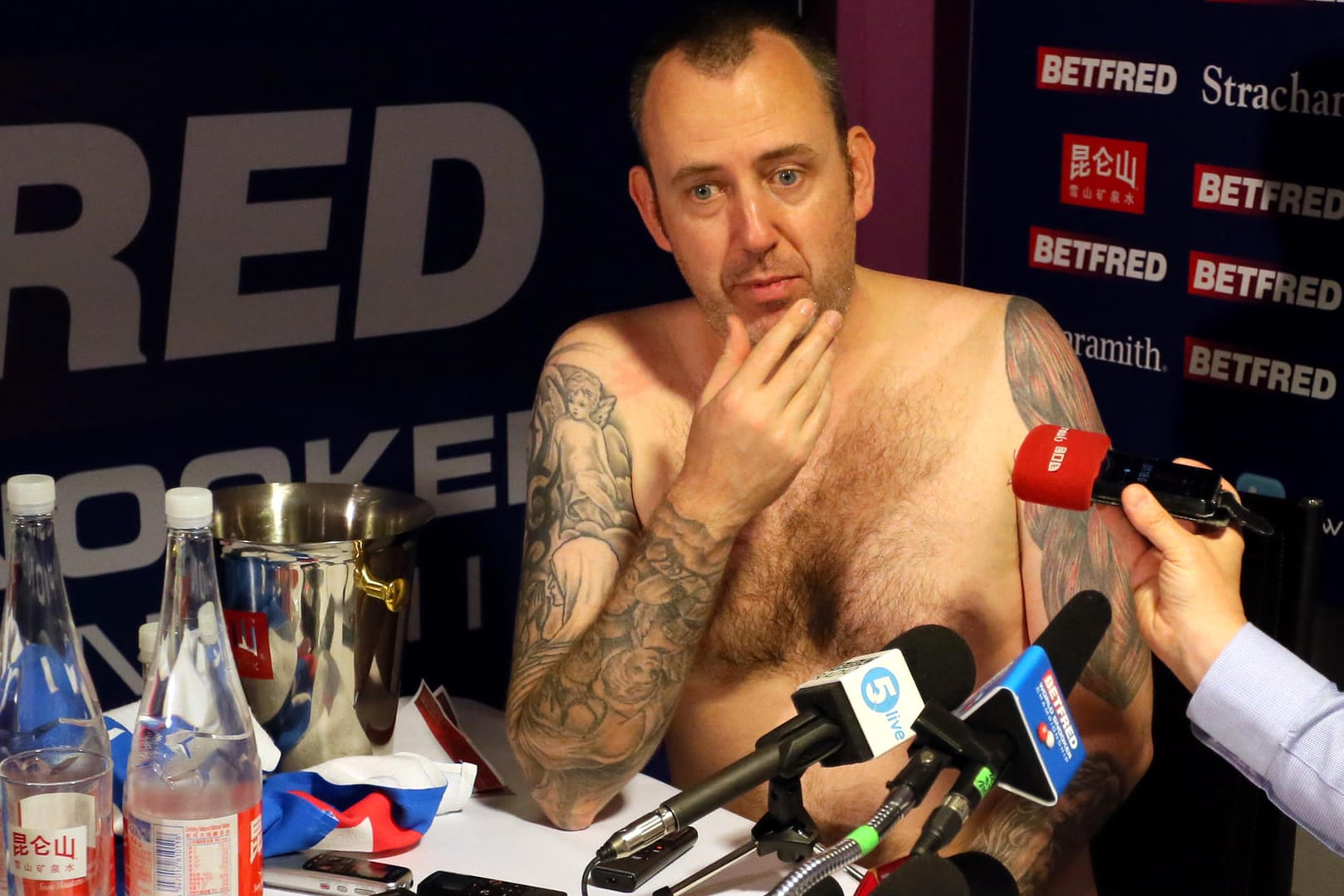 Mark Williams hat sich tatsächlich seiner Klamotten entledigt und sitzt bei der Pressekonferenz.