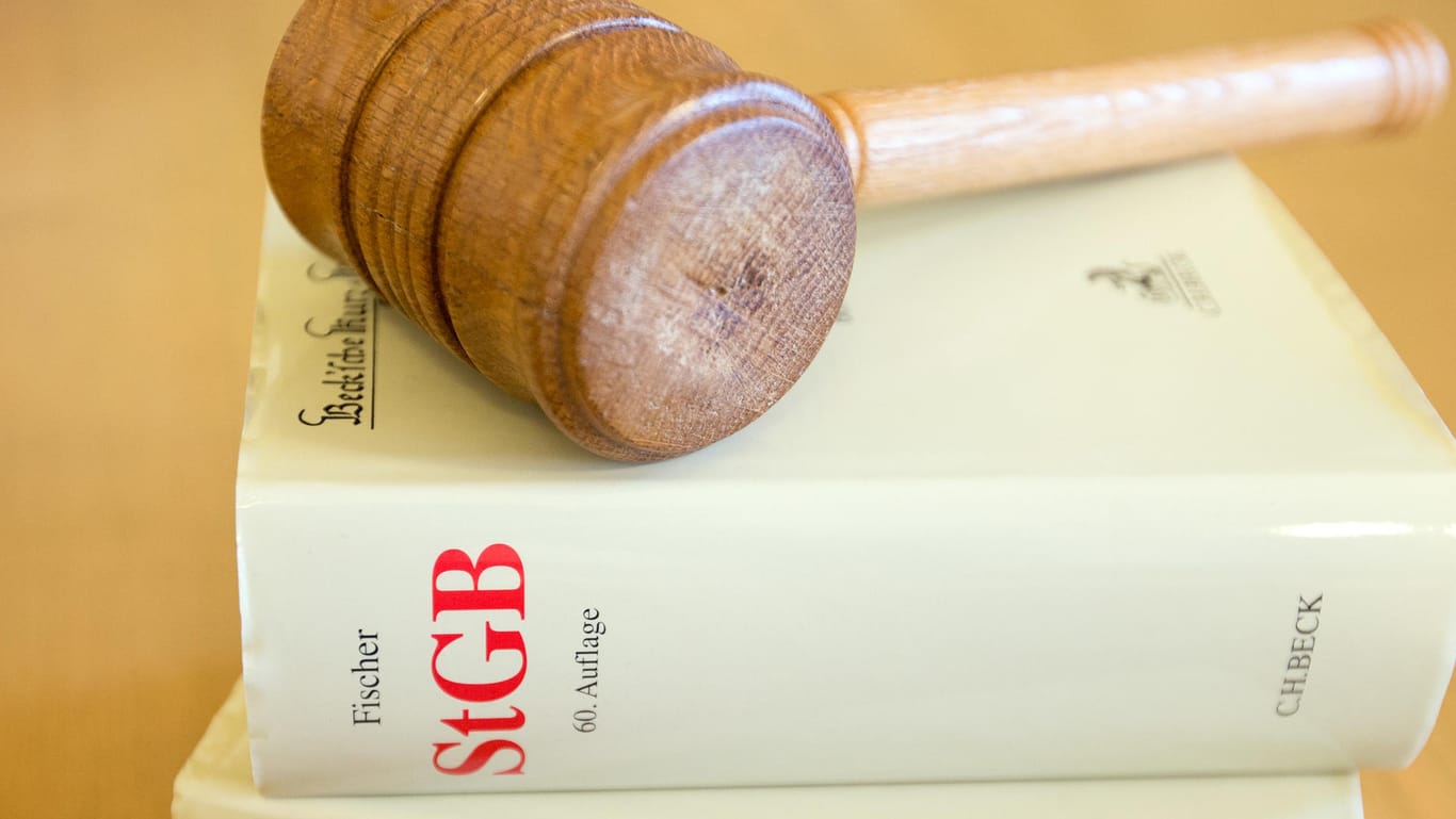 Ein Richterhammer und ein Strafgesetzbuch liegen auf einem Tisch: Prozess gegen mutmaßlichen Schleuser eröffnet