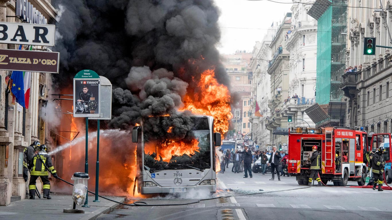 Die Feuerwehr versucht den brennenden Bus zu löschen: Auch ein zweiter Bus stand am selben Tag in Rom in Flammen.