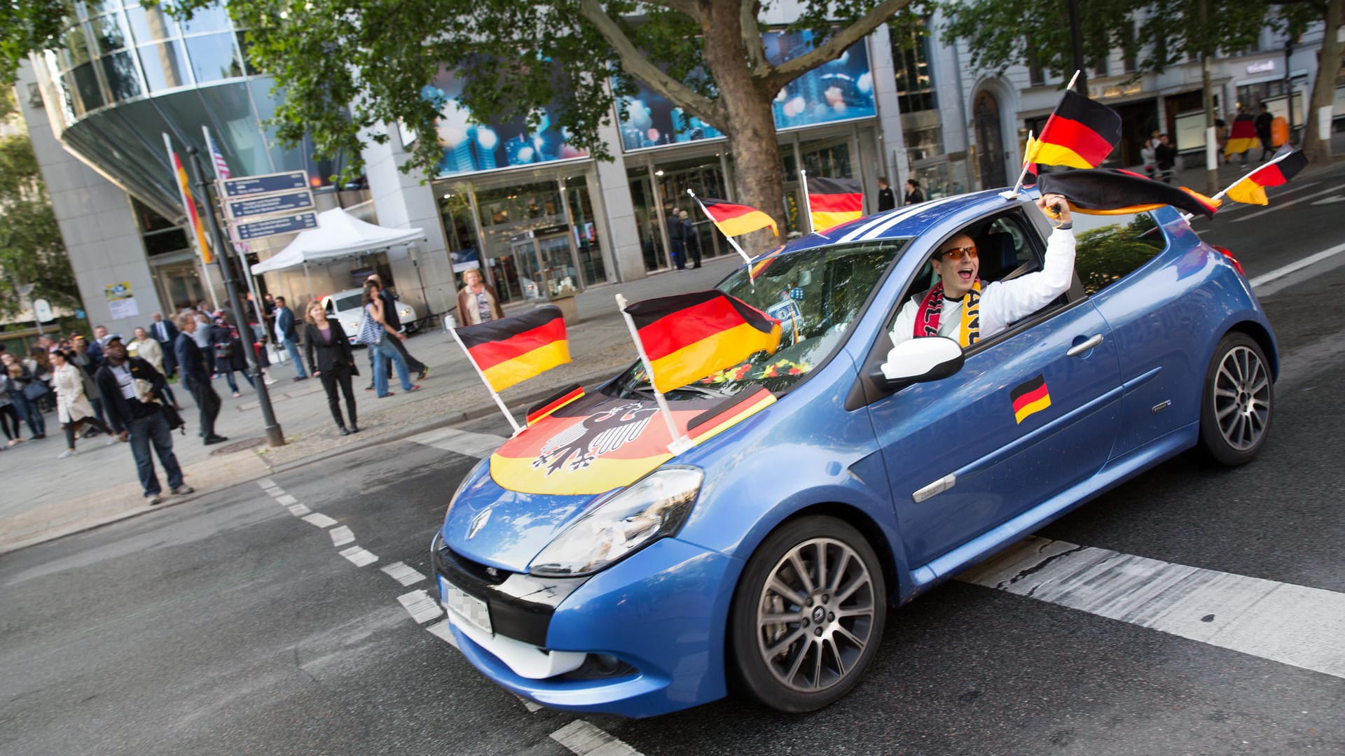 Fähnchen im Fahrtwind: Die Flaggen am Auto dürfen die Verkehrssicherheit nicht gefährden. Spätestens vor der Fahrt über die Autobahn nehmen Fans sie besser ab.