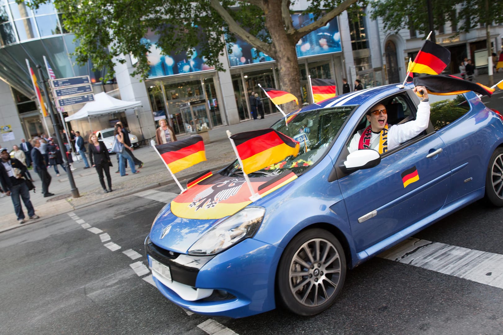 Fähnchen im Fahrtwind: Die Flaggen am Auto dürfen die Verkehrssicherheit nicht gefährden. Spätestens vor der Fahrt über die Autobahn nehmen Fans sie besser ab.