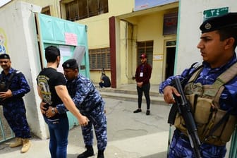 Ein Sicherheitsbeamter durchsucht einen Wähler vor einem Wahllokal in Bagdad.