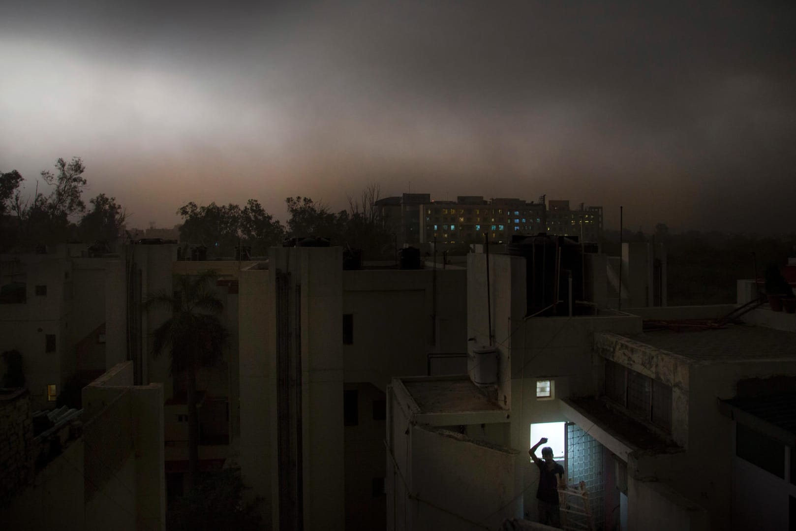 Ein Mann in Neu Delhi steht auf dem Balkon eines Apartments während eines plötzlichen Sturms: In Indiens Hauptstadt sind zwei Menschen bei schweren Gewittern gestorben.