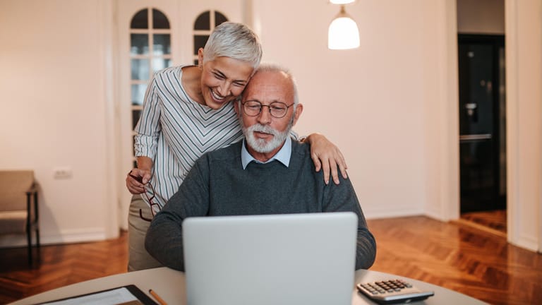 Älteres Ehepaar blickt auf Laptop: Mit der privaten Altersvorsorge können Beamte die Pensionslücke im Alter ausgleichen.