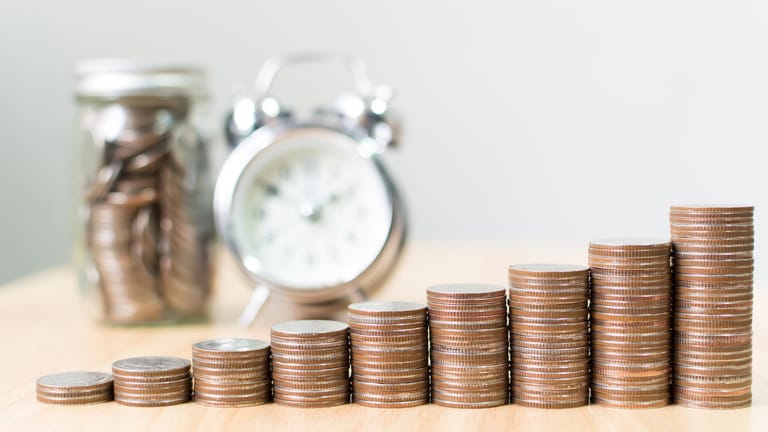 Ansteigende Stapel an Münzen vor einer tickenden Uhr: Mit Investitionen am Kapitalmarkt lässt sich ein Finanzpolster für den Ruhestand aufbauen.