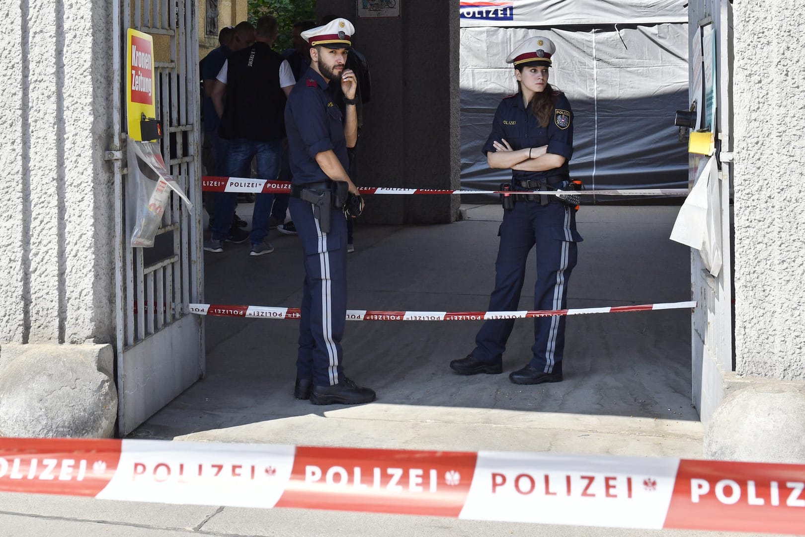 Polizisten stehen hinter einer Absperrung vor einer Wohnanlage, nachdem der Leichnam eines Mädchens in einem Müllcontainer entdeckt worden ist: Zum Stand der Fahndung äußerten sich die Behörden nicht.
