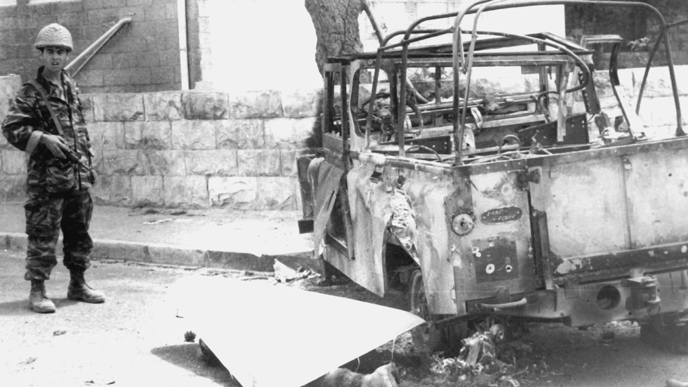 07.06.1967: Ein israelischer Soldat steht in der von Israel eroberten Altstadt von Jerusalem neben der abgedeckten Leiche eines jordanischen Soldaten und einem ausgebrannten Militärfahrzeug.