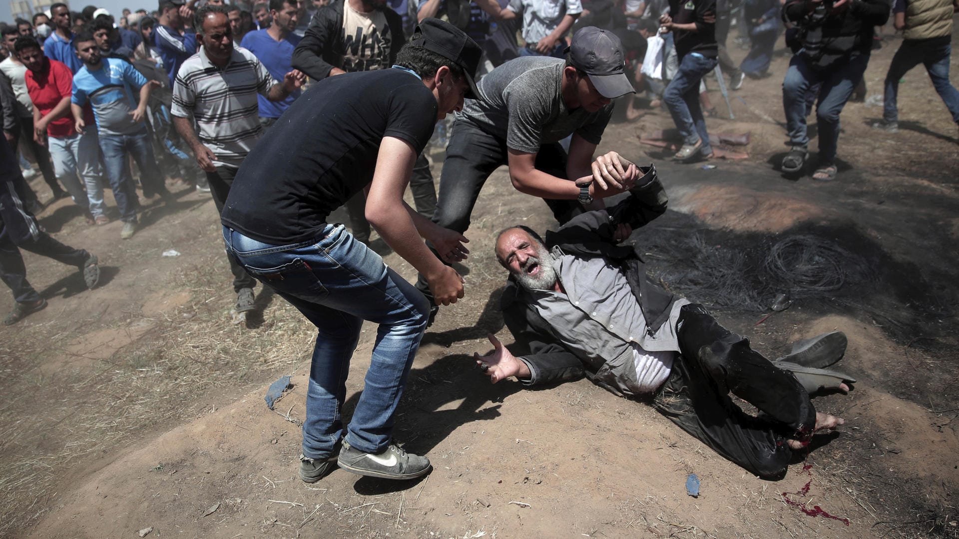 14.05.2018: Palästinenser helfen einem Verletzten bei Auseinandersetzungen mit israelischen Truppen an der Grenze zwischen dem Gazastreifen und Israel.