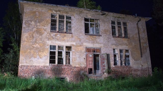 Scheinwerfer strahlen das Haus an, in dem sich der gesuchte mutmaßliche Gewalttäter verschanzt hatte.