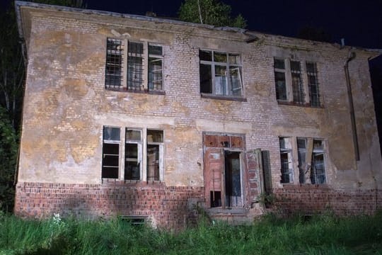 Scheinwerfer strahlen das Haus an, in dem sich der gesuchte mutmaßliche Gewalttäter verschanzt hatte.