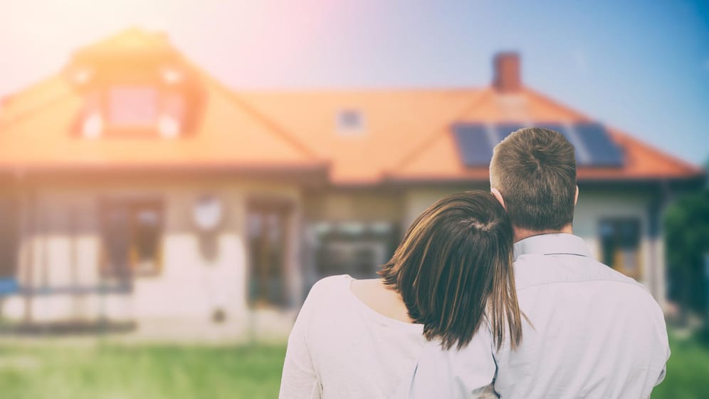 Junges Paar blickt auf ein Haus: Das derzeitige Niedrigzinsniveau bietet Immobilienbesitzern gute Finanzierungsbedingungen für das Eigenheim.