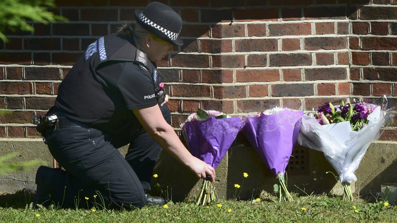 Eine britische Polizistin legt Blumen am Haus der al-Hilis nieder. Wer die drei Familienmitglieder tötete, konnte bis heute nicht geklärt werden. Die beiden jungen Töchter kamen in eine Pflegefamilie.