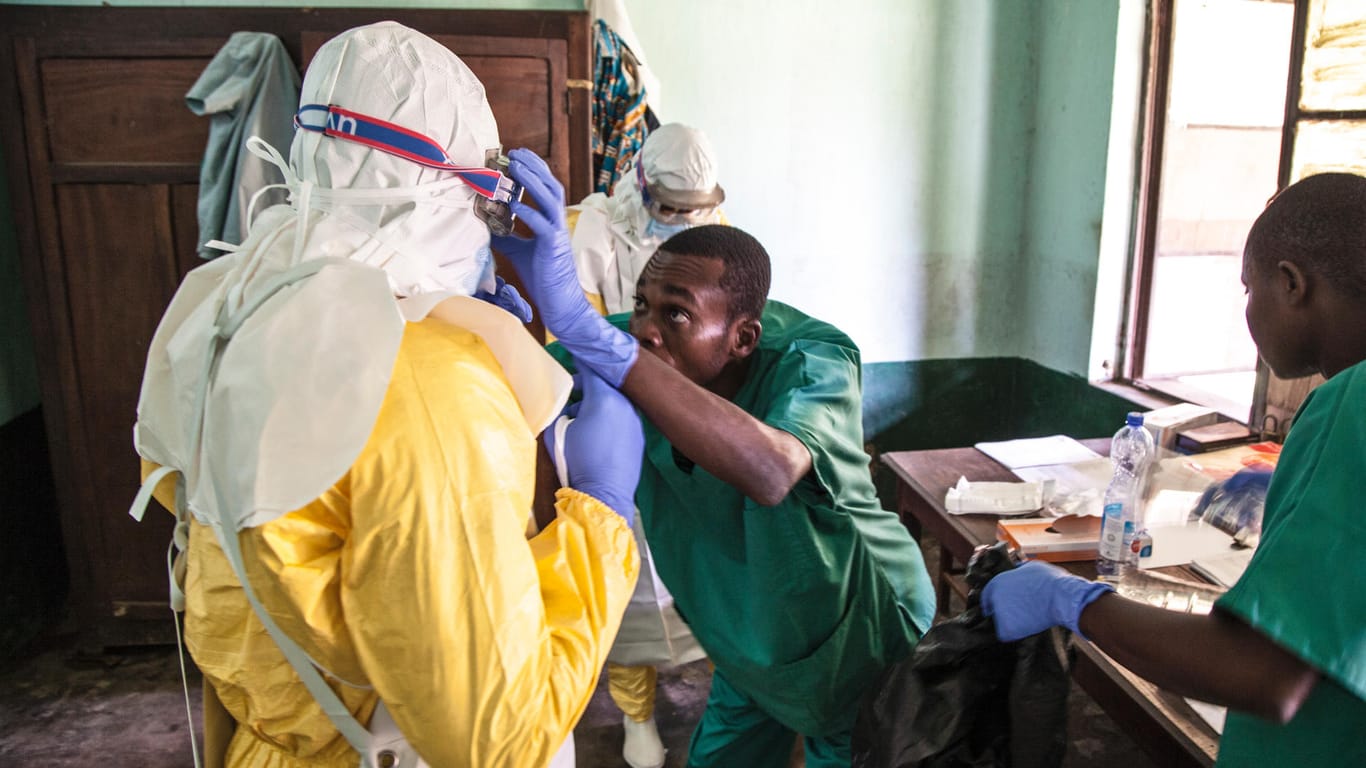 Medizinisches Personal zieht sich Schutzkleidung an, um Patienten zu behandeln, bei denen ein Verdacht auf Ebola vorliegt: Demnächst sollen Mediziner eine experimentelle Ebola-Impfung erhalten.