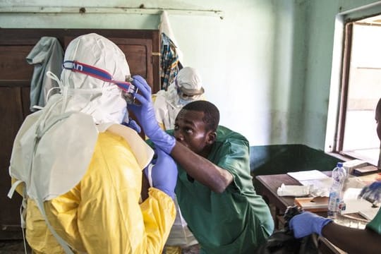 Mitarbeiter des Gesundheitswesens ziehen in einem Behandlungszentrum Schutzausrüstungen gegen Viren an, bevor sie Patienten in der Isolationsabteilung behandeln.