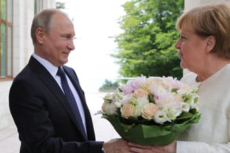 Putin überreicht Merkel Blumen: Die Atmosphäre soll lockerer sein als bei vorherigen Treffen.