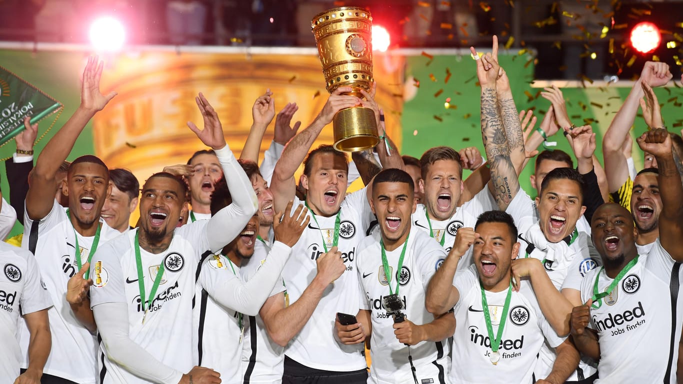 Alex Meier (Mitte) von Eintracht Frankfurt und seine Teamkollegen jubeln über dem Sieg mit dem Pokal bei der Siegerehrung auf dem Podium.