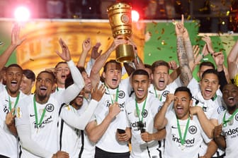 Alex Meier (Mitte) von Eintracht Frankfurt und seine Teamkollegen jubeln über dem Sieg mit dem Pokal bei der Siegerehrung auf dem Podium.