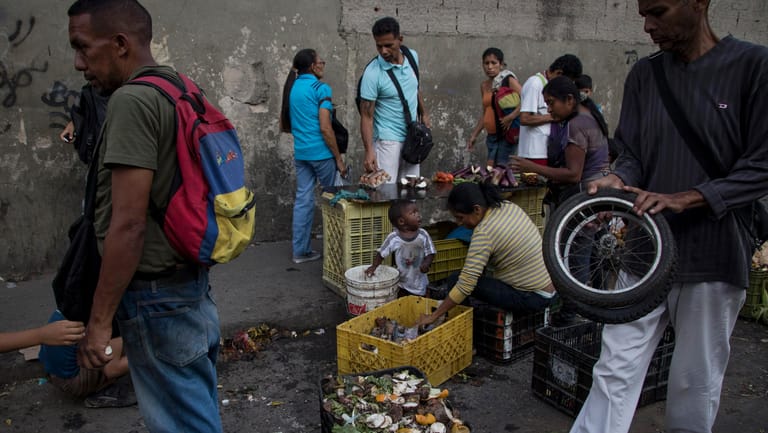 Straßenszene in Caracas: Venezolaner sammeln in der Nähe eines Straßenmarkts Gemüse- und Obstreste auf.