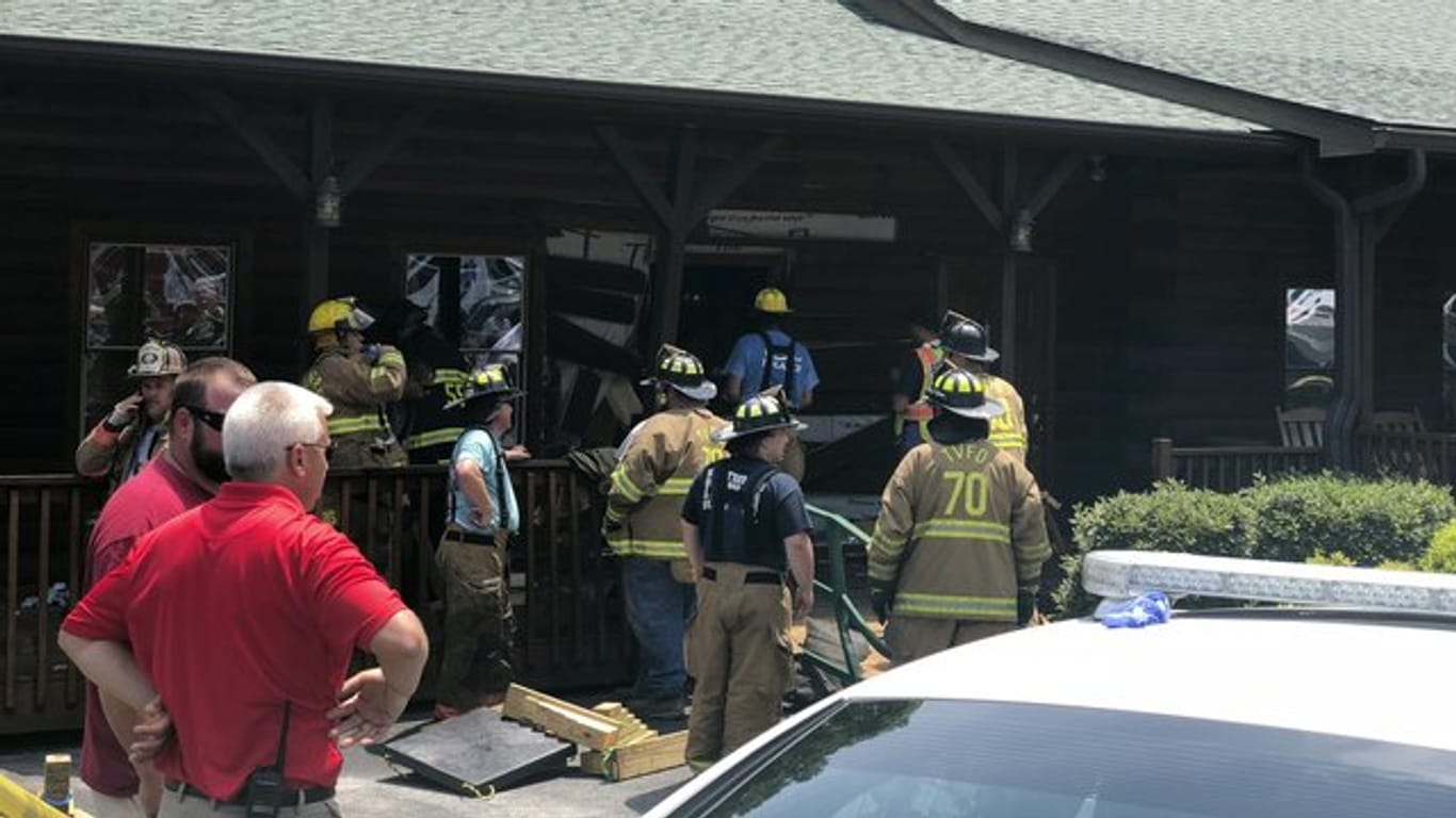 Einsatzkräfte der Feuerwehr stehen vor einem Restaurant, in das ein Mann sein Auto gelenkt hat.