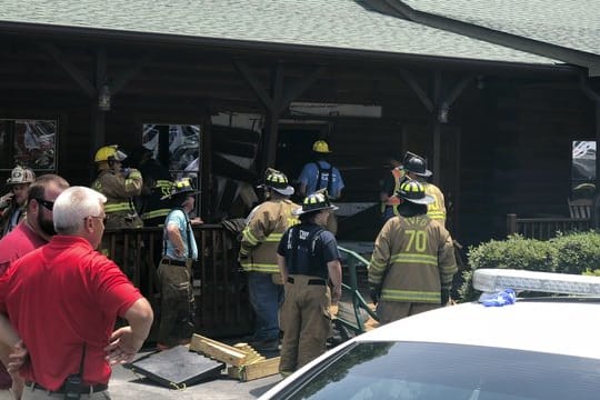 Einsatzkräfte der Feuerwehr stehen vor einem Restaurant, in das ein Mann sein Auto gelenkt hat.