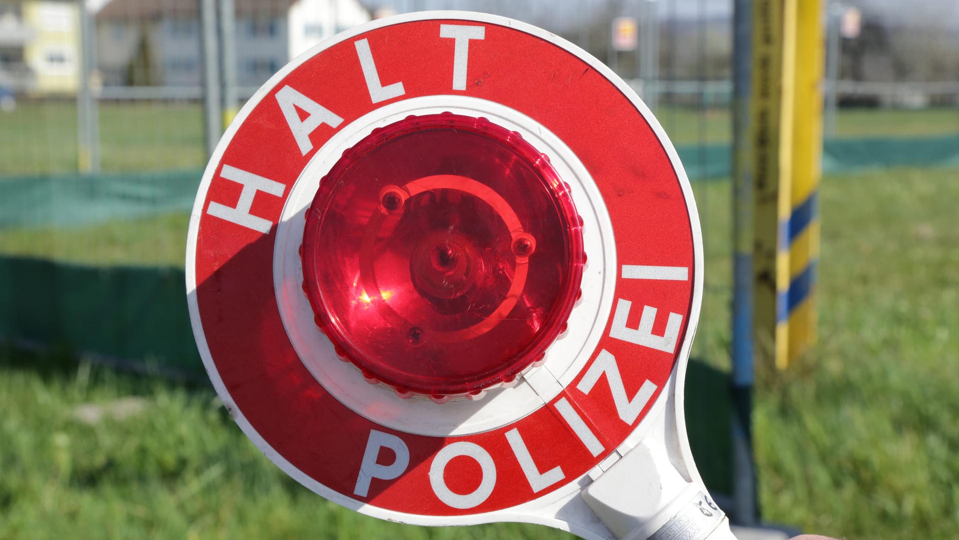 Polizist mit einer Kelle in der Hand: Polizei stoppt Trunkenfahrten – erst vom Sohn und dann vom Vater. Polizist mit einer Kelle in der Hand: Polizei stoppt Trunkenfahrten – erst vom Sohn und dann vom Vater.